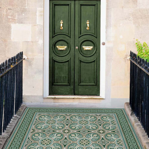 Entrance doorway featuring Europa Toulouse 20x20cm Victorian Moroccan style floor tiles in green and cream tones, installed with a decorative border and styled with dark green doors, stone walls and black railings.