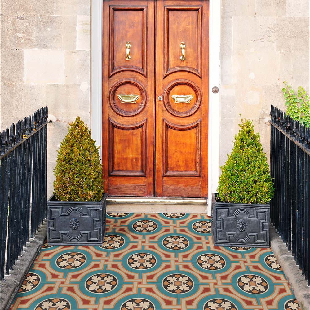 Entrance doorway featuring Europa Helsinki 20x20cm Victorian Moroccan style floor tiles in teal, terracotta and cream tones, installed in a decorative porch setting with wooden doors, stone walls and potted plants.
