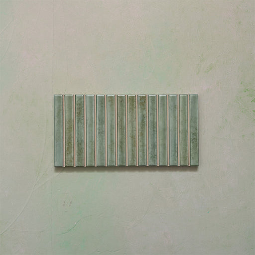 Product display of Elazar Decor Agave Green 12.5x25cm ceramic wall tiles in soft green tones, featuring a linear fluted design, handcrafted glossy finish and subtle tonal variation for textured contemporary interiors.