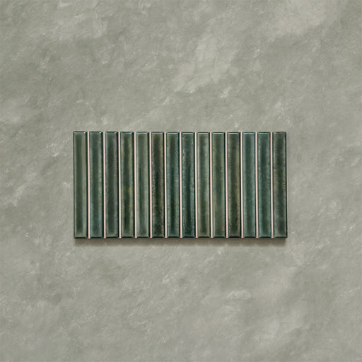 Product display of Elazar Decor Forest Green 12.5x25cm ceramic wall tiles in deep green tones, featuring a linear fluted design, handcrafted glossy finish and subtle tonal variation for textured contemporary interiors.