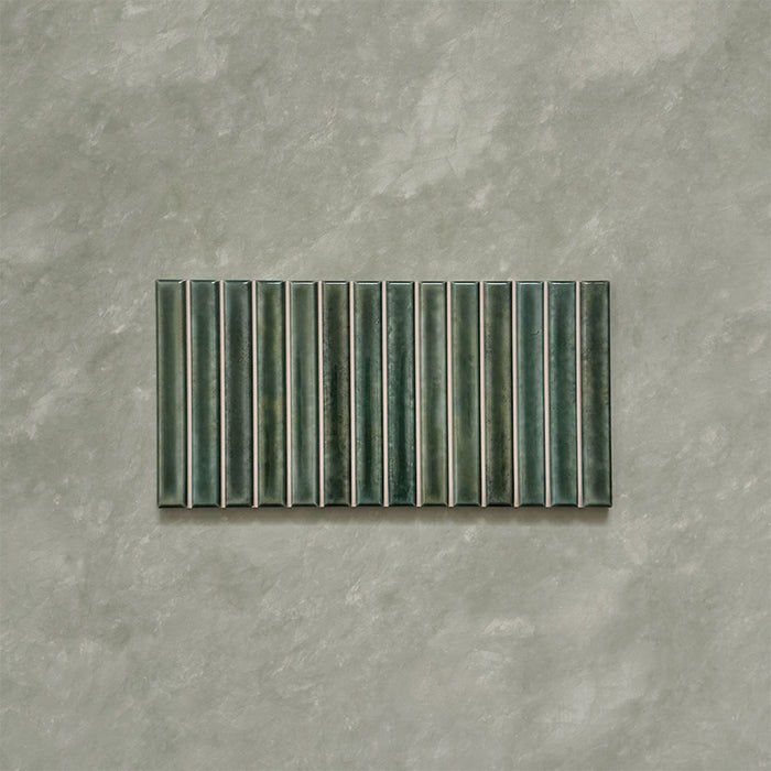 Product display of Elazar Decor Forest Green 12.5x25cm ceramic wall tiles in deep green tones, featuring a linear fluted design, handcrafted glossy finish and subtle tonal variation for textured contemporary interiors.