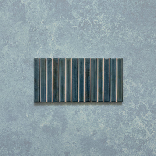 Product display of Elazar Decor Prussian 12.5x25cm ceramic wall tiles in deep blue tones, featuring a linear fluted design, handcrafted glossy finish and subtle tonal variation for textured contemporary interiors.