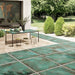 Outdoor patio featuring Elements Oxide 2cm thick porcelain floor tiles in a metallic effect finish, styled with contemporary garden furniture, timber-effect steps, built-in planters and modern landscaping for a luxurious outdoor living space.