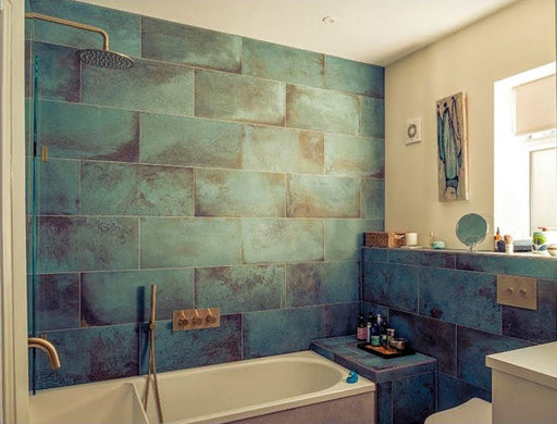 Contemporary bathroom featuring Elements Oxide 30cm x 60cm metallic effect wall and floor tiles, styled with a built-in bath, brass shower fittings and rich blue-green tones for a luxurious interior.