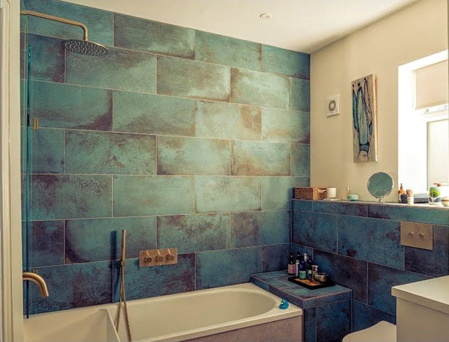 Contemporary bathroom featuring Elements Oxide 30cm x 60cm metallic effect wall and floor tiles, styled with a built-in bath, brass shower fittings and rich blue-green tones for a luxurious interior.