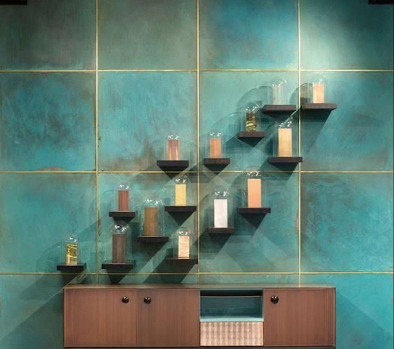 Contemporary interior featuring Elements Oxide 60cm x 60cm metallic effect wall tiles, paired with timber cabinetry and minimalist shelving to create a striking industrial-inspired feature wall with rich blue-green tones.