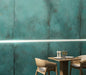 Contemporary dining area featuring Elements Oxide 60cm x 60cm metallic effect wall tiles, paired with light wood furniture and subtle LED lighting to create a bold industrial-inspired feature wall.
