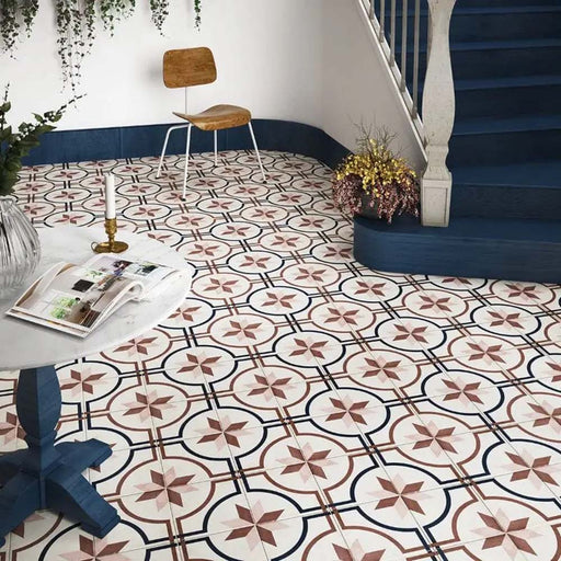 Entryway featuring Carnaby Rose Victorian-style 20x20cm porcelain wall and floor tiles, showcasing a pink and navy geometric pattern, styled with navy staircase details, trailing greenery, and minimalist wooden furniture.