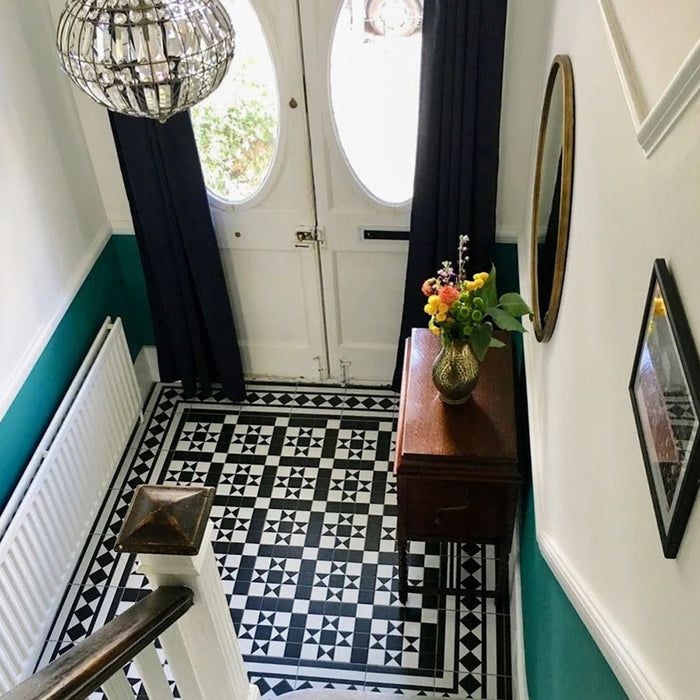 Entryway featuring Sloane Square Black and White 25x25cm Victorian-style ceramic floor tiles, arranged in a traditional geometric pattern with a matching border, styled with teal walls, a wooden side table, and a glass pendant light.