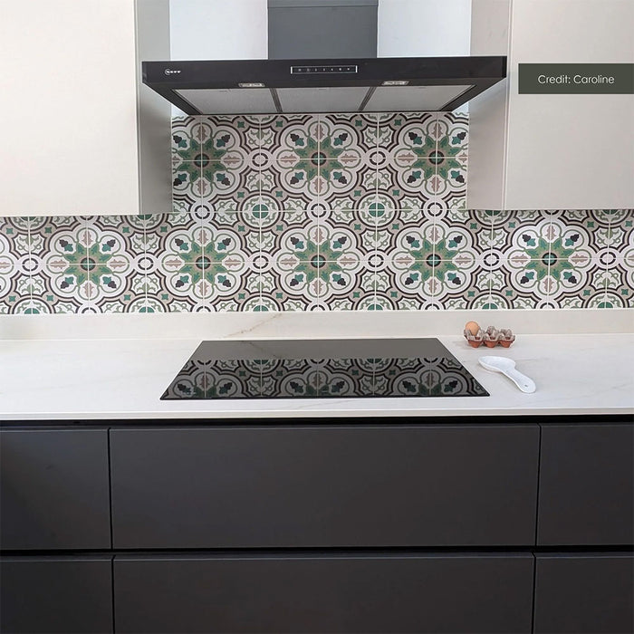 Contemporary kitchen featuring Europa Budapest 20x20cm Victorian and Moroccan-style patterned splashback tiles, with intricate green, grey and white floral geometric motifs, paired with dark grey cabinetry, white worktops and a black hob.