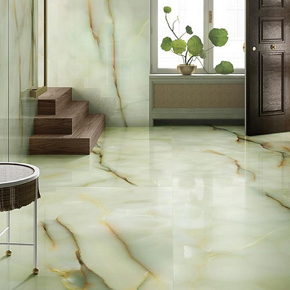 Interior space featuring Fantasia Jade Green Onyx Matt 60 × 120cm stone effect floor and wall tiles, with soft green tones and flowing gold veining, paired with wooden steps, natural light, and minimal styling.