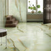 Interior space featuring Fantasia Jade Green Onyx Matt 60 × 120cm stone effect floor and wall tiles, with soft green tones and flowing gold veining, paired with wooden steps, natural light, and minimal styling.