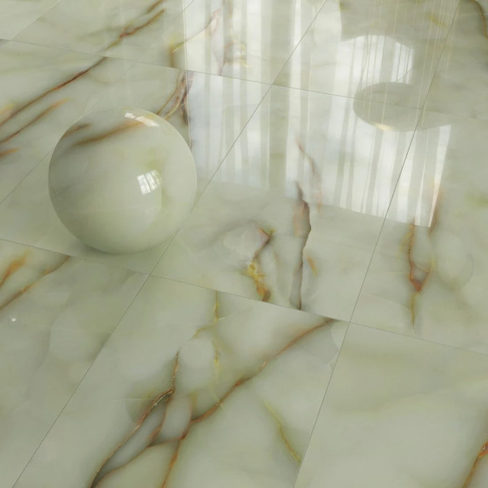 Close-up of Fantasia Jade Green Onyx Polished 60 × 120cm stone effect floor tiles, featuring soft green tones with flowing gold and amber veining, paired with a decorative sphere to highlight the high-gloss polished finish.