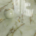 Close-up of Fantasia Jade Green Onyx Polished 60 × 120cm stone effect floor tiles, featuring soft green tones with flowing gold and amber veining, paired with a decorative sphere to highlight the high-gloss polished finish.
