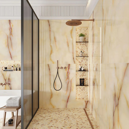 Walk-in shower featuring Fantasia Miele Onyx Matt 60 × 120cm stone effect wall tiles, styled with warm honey and amber veining across a soft cream base. The matt finish softens the natural onyx-inspired movement, paired with a coordinating mosaic shower floor, built-in niches, and brushed brass fittings for a calm, spa-like feel.