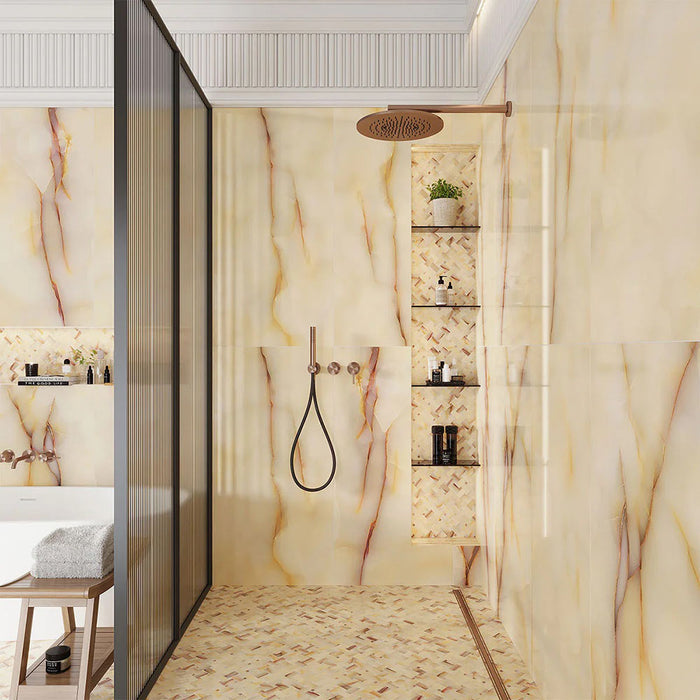Walk-in shower featuring Fantasia Miele Onyx Matt 60 × 120cm stone effect wall tiles, styled with warm honey and amber veining across a soft cream base. The matt finish softens the natural onyx-inspired movement, paired with a coordinating mosaic shower floor, built-in niches, and brushed brass fittings for a calm, spa-like feel.