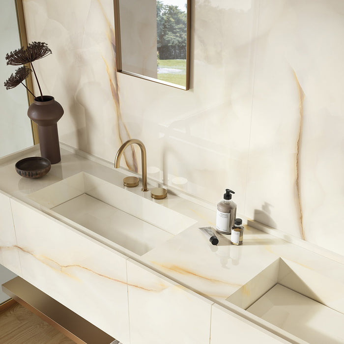 Bathroom vanity featuring Fantasia Pearl Onyx Polished 60 × 120cm stone effect wall tiles, with soft cream tones and delicate gold veining, paired with a double basin, brass fittings, and minimal styling.