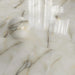 Close-up of Fantasia Pearl Onyx Polished 60 × 120cm stone effect floor tiles, featuring soft cream tones with subtle grey and gold veining, paired with a decorative sphere to highlight the high-gloss polished finish.