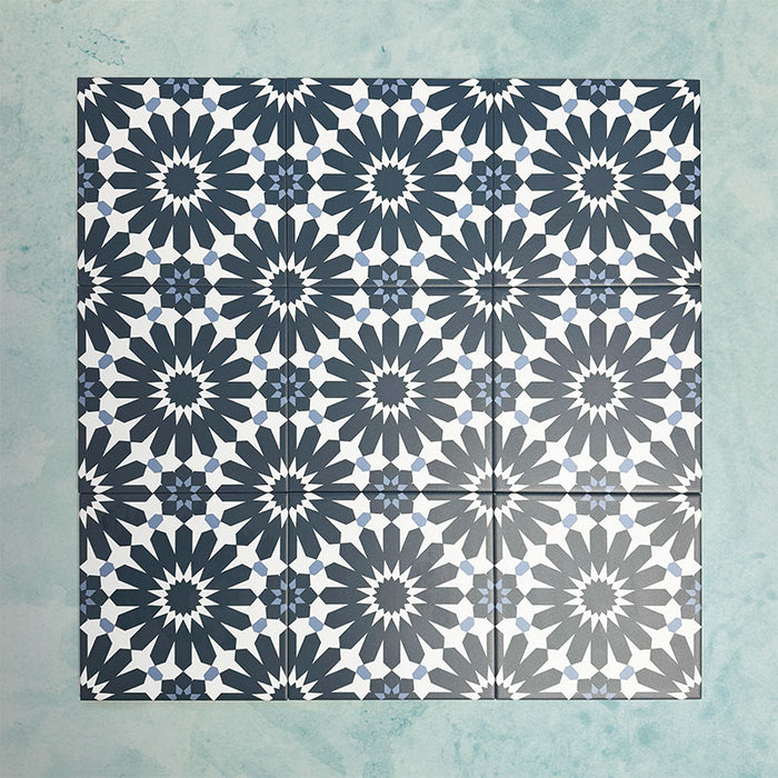 Arrangement of Fizaan Federal Blue 20x20cm Moroccan-style porcelain tiles, showcasing a repeating geometric pattern in deep blue and soft neutral tones.