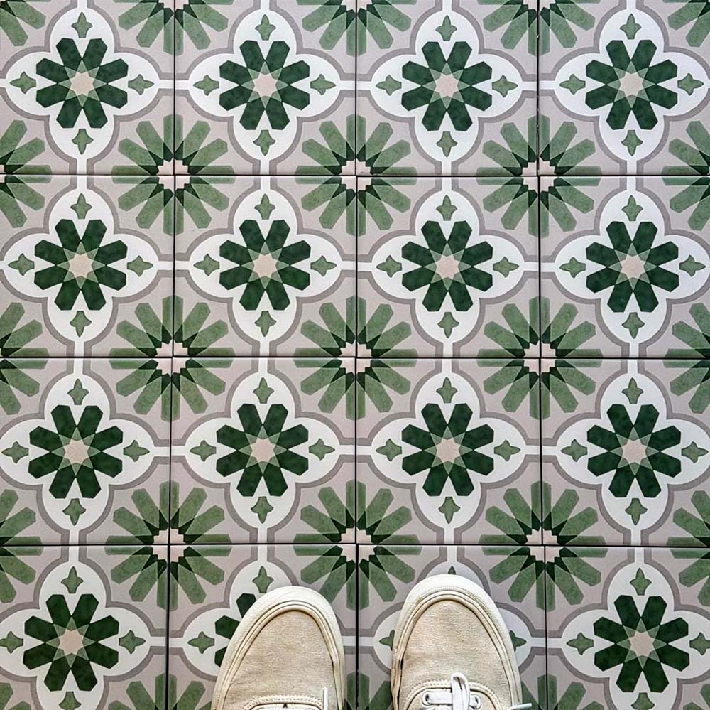 Top-down view featuring Clarence House Jade Mini 15x15cm Victorian Moroccan-style porcelain floor tiles, styled with cream trainers to highlight the soft green and white geometric pattern.