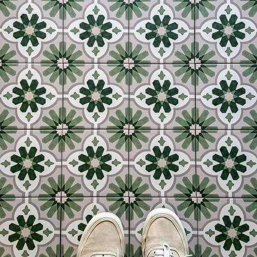 Top-down view featuring Clarence House Jade Mini 15x15cm Victorian Moroccan-style porcelain floor tiles, styled with cream trainers to highlight the soft green and white geometric pattern.