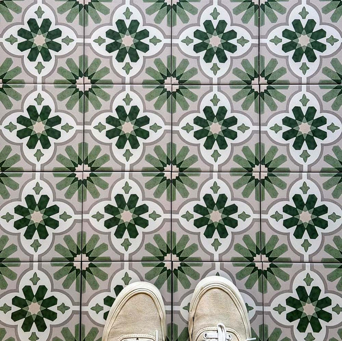 Top-down view featuring Clarence House Jade Mini 15x15cm Victorian Moroccan-style porcelain floor tiles, styled with cream trainers to highlight the soft green and white geometric pattern.