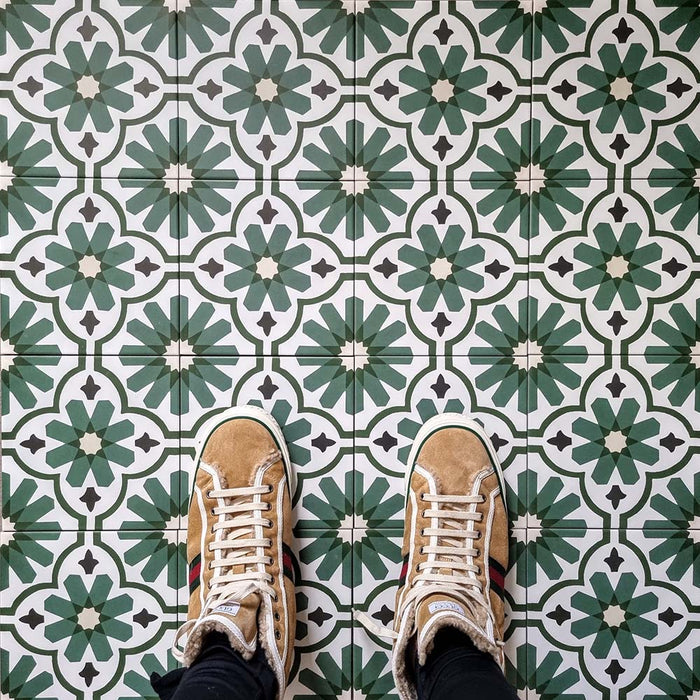 Top-down view featuring Clarence House Verde Green 20x20cm Victorian Moroccan-style porcelain floor tiles, styled with tan suede shoes to highlight the bold green and white geometric pattern.