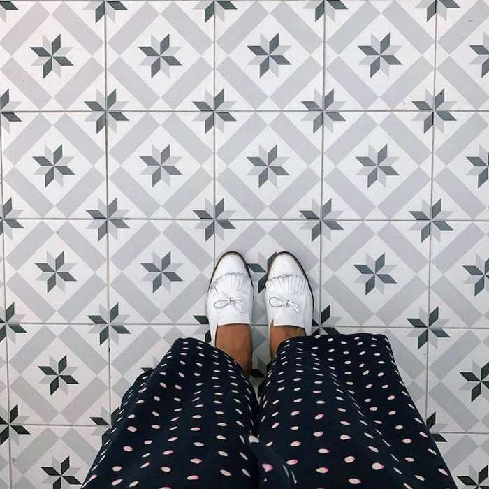 Overhead lifestyle view of Georgetown Star Victorian-style 20x20cm patterned porcelain floor tiles, showing the repeating star motif beneath white shoes.