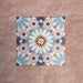 Arrangement of Fizaan Fiera 20x20cm Moroccan-style porcelain tiles, showcasing a repeating geometric pattern in soft blue, red and neutral tones.