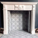 Alhambra Palacio 20x20cm Moroccan tiles styled inside a classic white fireplace, featuring an elegant black and white geometric cross pattern that adds a striking modern contrast to a traditional mantelpiece.
