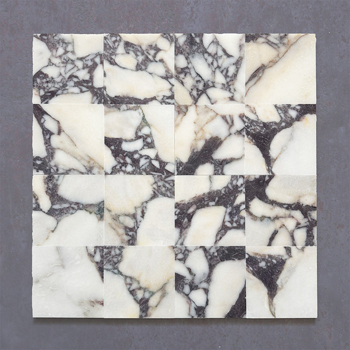 Fitzrovia Calacatta Viola honed natural marble tile in a 15.2cm x 15.2cm square format, featuring a creamy white background with bold purple veining and subtle warm gold tones, creating a luxurious and timeless natural stone finish.