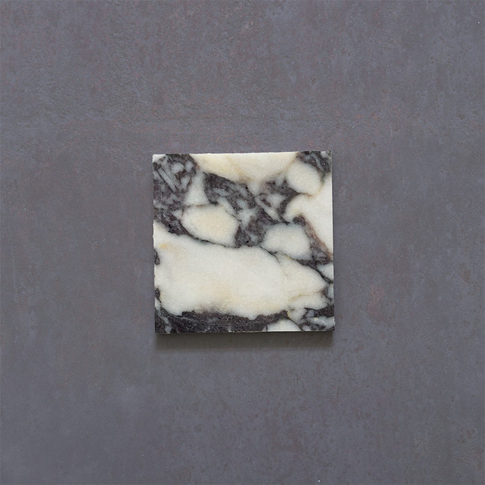 Close-up of Fitzrovia Calacatta Viola honed natural marble tile in a 15.2cm x 15.2cm square format, featuring a creamy white background with bold purple veining and subtle warm gold tones, creating a luxurious and timeless natural stone finish.