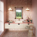 Bathroom featuring Fitzrovia Sylvester Pink Honed Finish Natural Marble 15.2cm x 15.2cm wall and floor tiles, paired with blush pink walls, a floating vanity, brass fittings, a stone basin and a vintage-inspired mirror.
