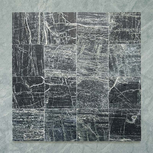 Fitzrovia Verde tumbled natural marble tile in a 15.2cm x 15.2cm square format, featuring deep forest green tones with natural white veining, textured tumbled edges and an authentic aged stone finish.
