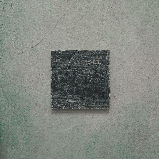 Close-up of Fitzrovia Verde tumbled natural marble tile in a 15.2cm x 15.2cm square format, featuring deep forest green tones with natural white veining, textured tumbled edges and an authentic aged stone finish.