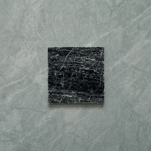 Close-up of Fitzrovia Verde tumbled natural marble tile in a 15.2cm x 15.2cm square format, featuring deep forest green tones with natural white veining, textured tumbled edges and an authentic aged stone finish.