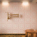 Close-up of Fizaan Pink 20x20cm Moroccan style kitchen wall tiles, featuring delicate pink and cream floral starburst patterns, creating a decorative splashback with brass fittings and copper cookware.