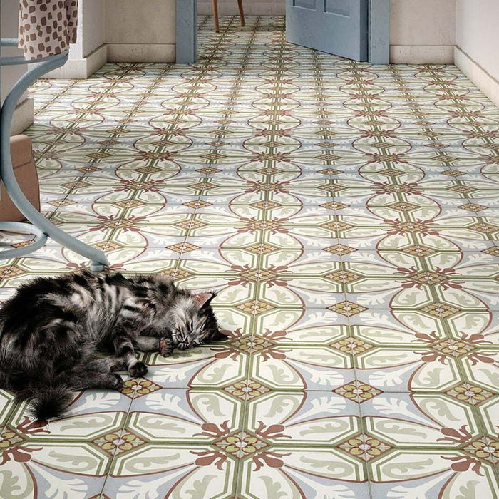 Floor setting featuring Carnaby Place Victorian-style 20x20cm porcelain wall and floor tiles, showcasing an ornate floral and geometric pattern in olive, blue, cream, and red tones, with a cat resting on the patterned surface in a cosy hallway scene.