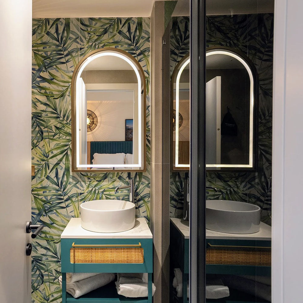 Bathroom featuring Forest Decor Light 60x120cm botanical-style wall tiles, showcasing a tropical leaf design in soft green and blue tones, paired with a teal vanity unit, illuminated mirror, white basin and contemporary fittings.