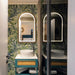 Bathroom featuring Forest Decor Light 60x120cm botanical-style wall tiles, showcasing a tropical leaf design in soft green and blue tones, paired with a teal vanity unit, illuminated mirror, white basin and contemporary fittings.