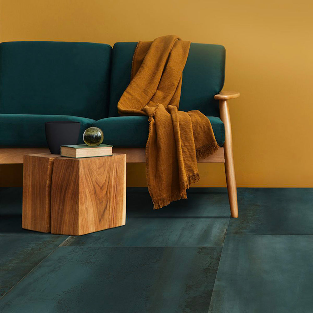 Living room setting featuring Furnace Cuprum Oxide Metallic 60 × 60cm porcelain floor tiles, showcasing rich copper-toned hues with subtle tonal variation and a softly textured metallic effect, paired with warm wood furniture and deep upholstery for a bold, contemporary finish.