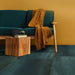 Living room setting featuring Furnace Cuprum Oxide Metallic 60 × 60cm porcelain floor tiles, showcasing rich copper-toned hues with subtle tonal variation and a softly textured metallic effect, paired with warm wood furniture and deep upholstery for a bold, contemporary finish.
