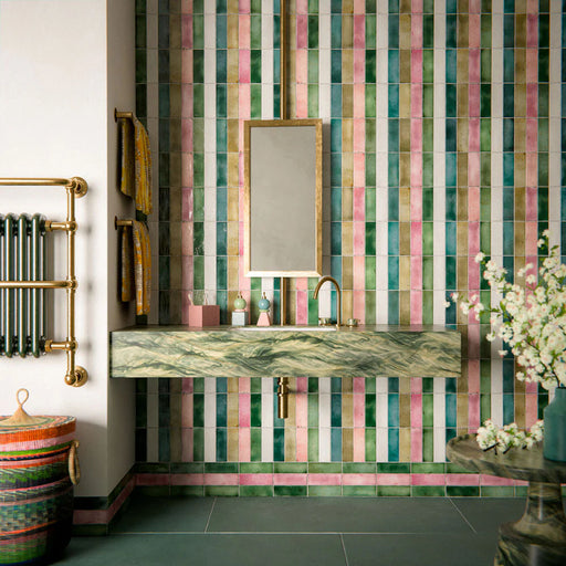 Bathroom interior featuring Furnace Emerald Green Oxide Metallic 60 × 120cm porcelain floor tiles, styled with rich green tones and soft tonal variation, paired with a colourful striped feature wall, brass fittings, and a marble-effect vanity for a bold, design-led finish.