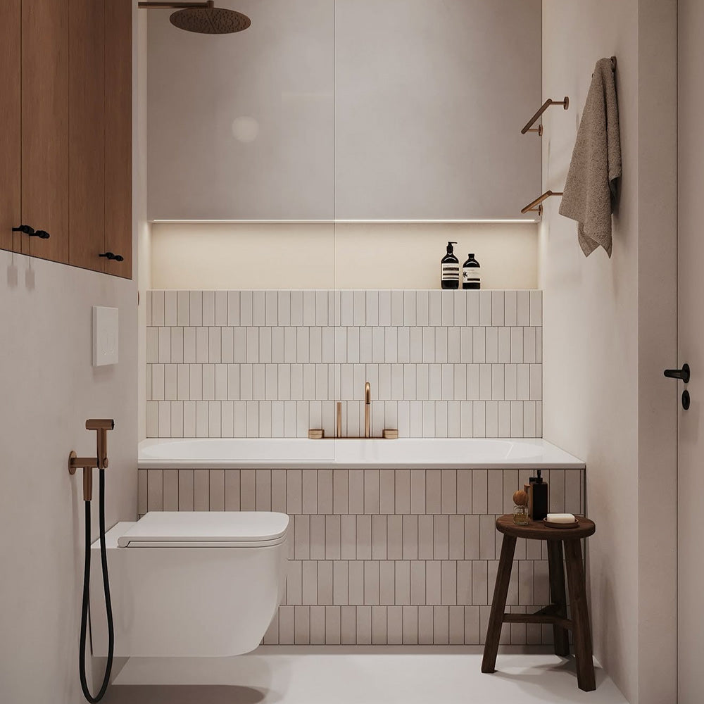 Bathroom interior featuring Fusion Bricks Artic White 6.5 × 20cm ceramic wall tiles, laid vertically with a clean, uniform look, paired with a built-in bath, brass fittings, soft lighting, and minimalist neutral styling.