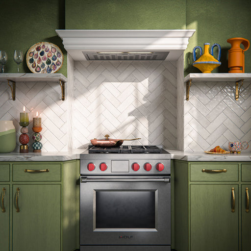 Kitchen interior featuring Fusion Bricks Chalk White 6.5 × 20cm ceramic wall tiles, laid in a herringbone pattern with a glossy finish, paired with green cabinetry, marble worktops, and a range cooker for a classic, design-led look.