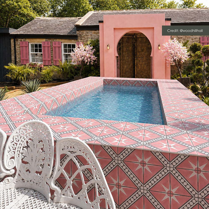 Outdoor swimming pool area featuring Galata Pink 20cm x 20cm Moroccan style tiles across the pool surround and sides, showcasing a bold pink geometric star pattern against a coordinating pink exterior.