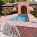 Outdoor swimming pool area featuring Galata Pink 20cm x 20cm Moroccan style tiles across the pool surround and sides, showcasing a bold pink geometric star pattern against a coordinating pink exterior.