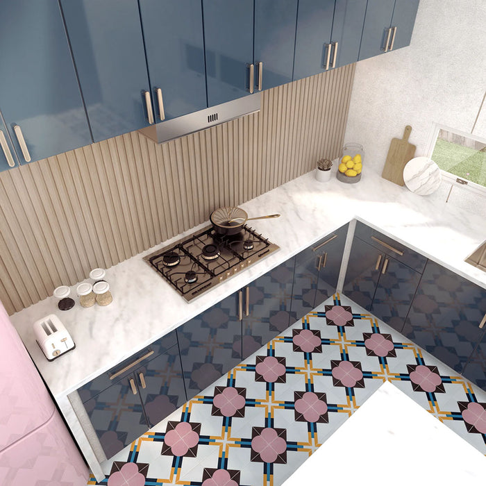Geometry Contour patterned tiles in a 20x20cm size used in a modern L-shaped kitchen, featuring pink circular motifs, mustard and teal intersecting lines, and brown geometric accents on a light base. The colourful tile design contrasts with glossy navy cabinets, marble countertops, a ribbed beige backsplash, and soft pastel appliances for a vibrant contemporary look.