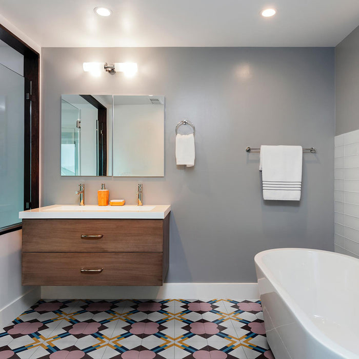 Bathroom featuring Geometry Contour 20x20cm patterned floor tiles, showcasing pink circular motifs with mustard, teal, and navy intersecting lines. Styled with a floating wooden vanity, double sinks, grey walls, chrome fixtures, and a modern freestanding bathtub for a clean contemporary look.