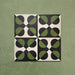 Group image showing four Geometry Illusion Verde Noir 20x20cm geometric patterned tiles arranged to create a circular repeat, featuring green and black semicircles with cream diamond intersections, photographed against a mottled green background.
